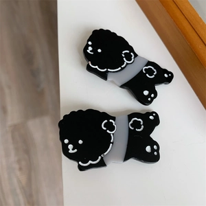 Detail view of two cute black dog-shaped acetate hair clips with grey stripe patterns