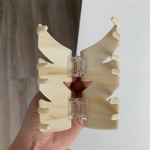 Detail of butterfly hair claw clip with cream marble texture and spring mechanism