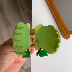 Dettaglio della molletta per capelli a forma di mela verde in acetato lucido con molla