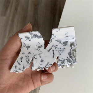 Detailed close-up of marble acetate hair claw clip with crystal and handmade text