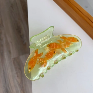 Détail de la pince à cheveux en acrylique vert translucide avec motifs de poissons