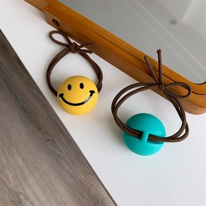 Close-up of yellow smiley face hair tie with elastic band and brown ribbon bow detail
