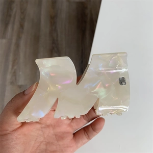 Macro shot of M-shaped acetate hair claw clip with iridescent finish and small rhinestone