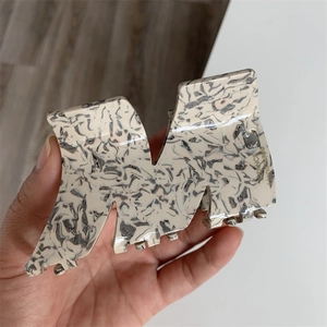 Detail of large acetate hair claw clip featuring black and white marble pattern in M shape