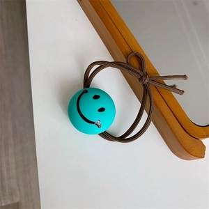 Detailed view of elastic brown hair tie with a cyan bead featuring a cute smiley face
