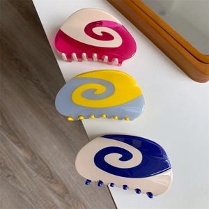 Close-up of three colorful swirl pattern acetate hair claws for bun styling