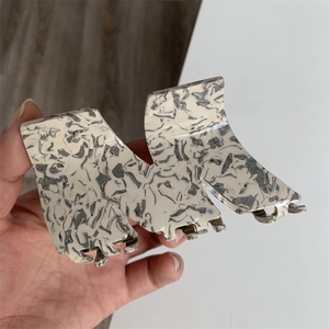 Close-up of M-shaped acetate hair claw clip with grey marble pattern and metal spring