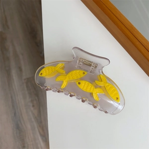 Vue détaillée de la pince à cheveux poisson rouge en acrylique avec petits poissons jaunes