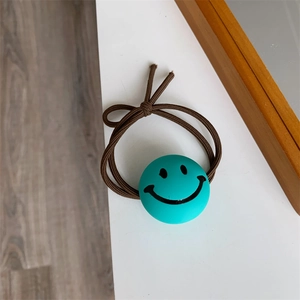 Close-up of elastic brown hair tie with a turquoise bead featuring a black smiley face