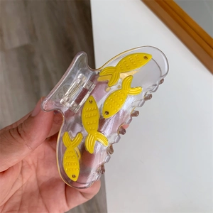 Détail de la pince à cheveux transparente ornée de petits poissons rouges jaunes et strass