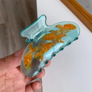 Détail de la pince à cheveux poisson en résine bleue avec motif de poisson rouge