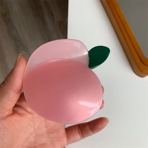 Dettaglio del fermaglio per capelli a forma di pesca rosa con foglie verdi lucide