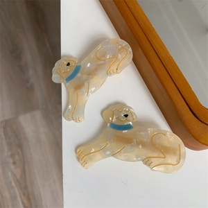 Detailaufnahme von zwei hündchenförmigen Acetat-Haarspangen mit Goldrand auf weißem Tisch