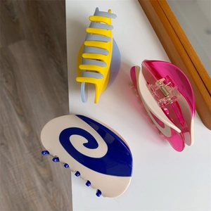 Detailed close-up showing three colorful acetate hair claws with swirl patterns and strong teeth