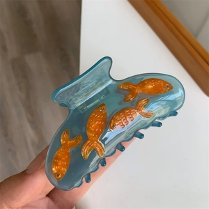 Détail de la pince à cheveux translucide bleue avec motifs de poissons et yeux en cristal