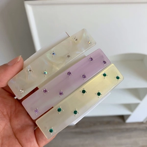 Close-up of geometric acetate hair clips with colorful rhinestones in three soft colors