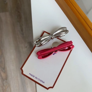 Détail de barrettes nœud en métal argenté et magenta sur carte de présentation