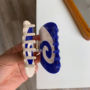 Close-up of cream and blue spiral swirl pattern on acetate hair claw clip with transparent hinge