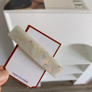 Macro shot of cream acetate hair clip with sparkling rhinestones on display card