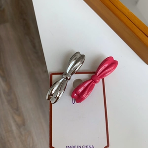 Paire de pinces à cheveux nśud en métal argenté et rose sur carte d'affichage