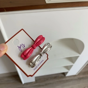 Vue détaillée des barrettes nœuds en laque rose et métal argenté sur porte-carte