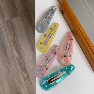 Detailed macro view of colorful butterfly hair clips with resin rhinestones in five pastel shades