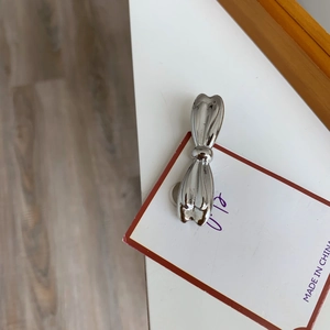 Détail macro d'une barrette à cheveux argentée en forme de nœud sur un support