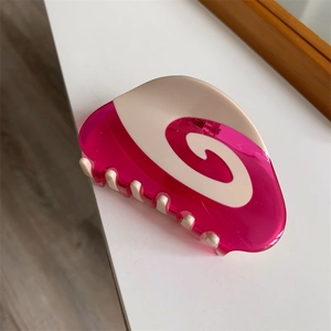 Macro shot of rose pink acetate hair claw with cream swirl pattern and metal spring