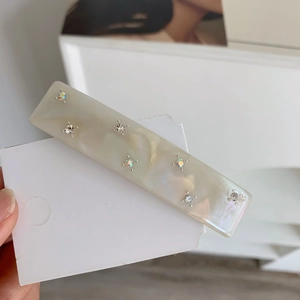Detail view of cream acetate hair clip with sparkling colorful crystals and marble texture