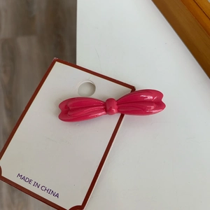 Vue détaillée d'une barrette à cheveux rose brillant en forme de nœud sur carte