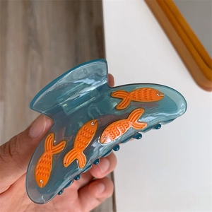 Gros plan sur la pince à cheveux poisson rouge en acrylique bleu avec strass brillants