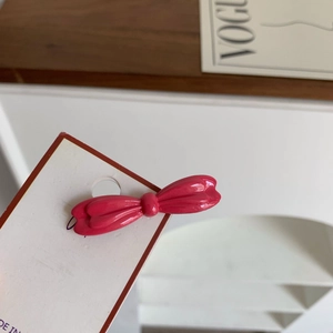 Vue détaillée d'une pince à cheveux nœud rose avec finition brillante sur carte