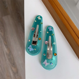 Detail of teal resin hair clips featuring colorful crystal butterfly and star decorations