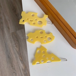 Vue détaillée des pinces à cheveux en résine en forme de fromage jaune texturé