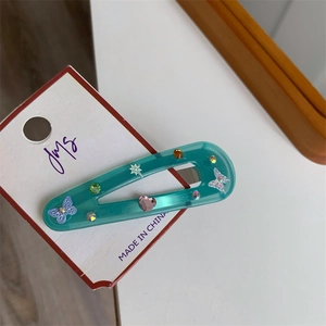 Macro detail of blue butterfly hair clip with colorful rhinestones on card