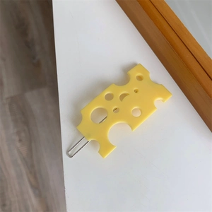 Détail d'une pince à cheveux créative en forme de fromage jaune avec base métallique