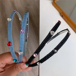 Detail view of denim headbands with heart-shaped colorful rhinestones in hand