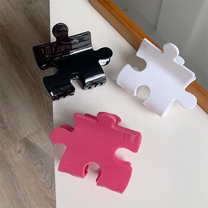 Detail showing creative puzzle-shaped hair claws in black, white, and pink resin material