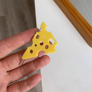 Détail d'une pince à cheveux jaune en forme de fromage avec trous et fermoir métal
