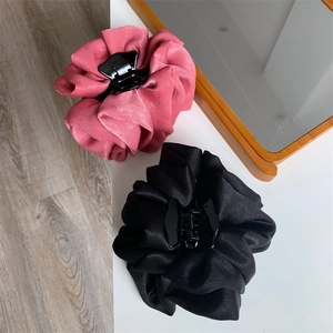 Détail de pinces à cheveux en satin élégant rose et noir avec des plis floraux