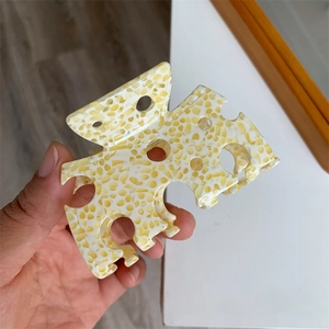 Vue détaillée d'une pince à cheveux jaune marbré avec design géométrique évidé moderne