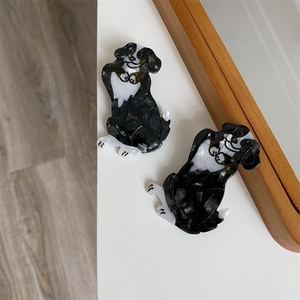 Detailansicht von zwei niedlichen schwarz-weißen Hunde-Haarklammern auf Holzgrund