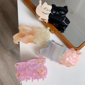 Detail of cute cat-shaped hair claws with marble textures in various colors on white table