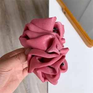 Détail de la pince à cheveux fleur en soie rose avec plis en tissu et perles noires
