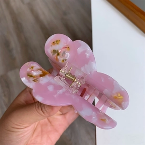Detailed close-up of a pink butterfly hair claw clip with marble texture and metal spring