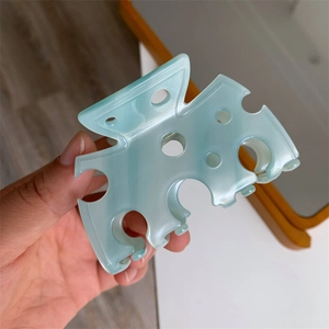 Détail de la pince à cheveux vert menthe en forme de fromage avec design évidé en acétate