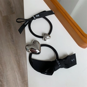 Detail view of black elastic hair ties with silver heart charms and printed ribbons
