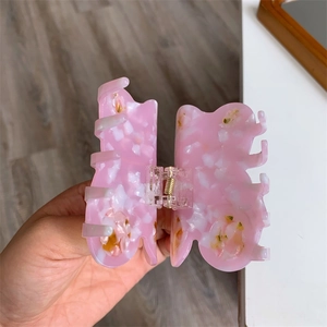 Detailed macro view of butterfly hair claw clip with pink marble acetate texture
