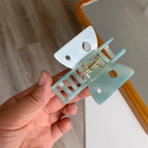Gros plan sur la pince à cheveux rectangulaire vert menthe avec motifs ajourés et ressort