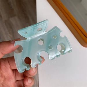 Détail de la pince à cheveux vert menthe avec un design ajouré style fromage suisse